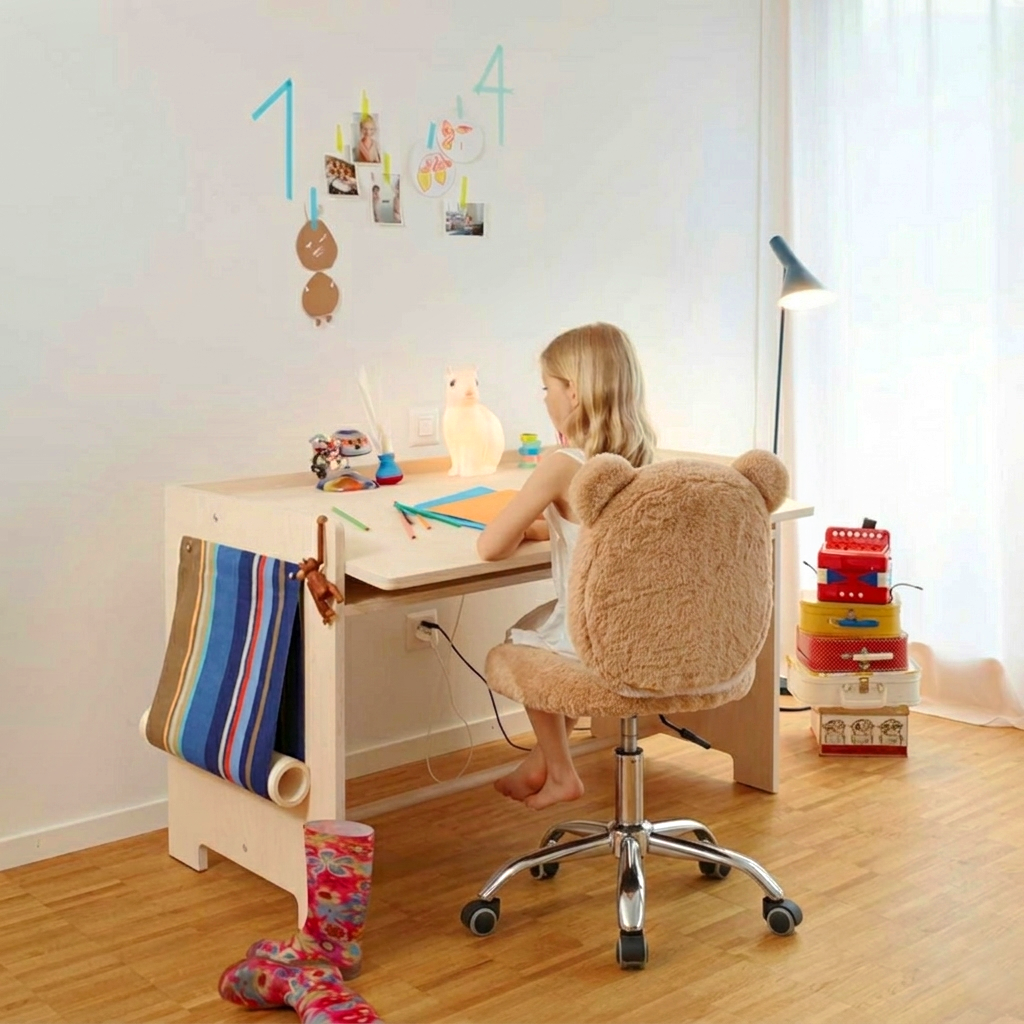 Child sitting at a desk in a room with toys and a lamp.